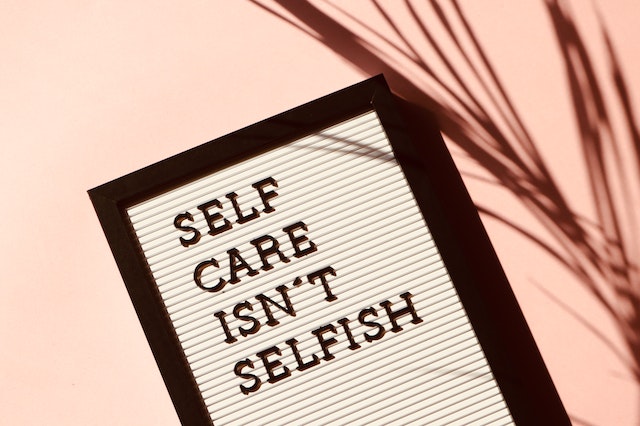 A letterboard sign reading "Self Care Isn't Selfish"